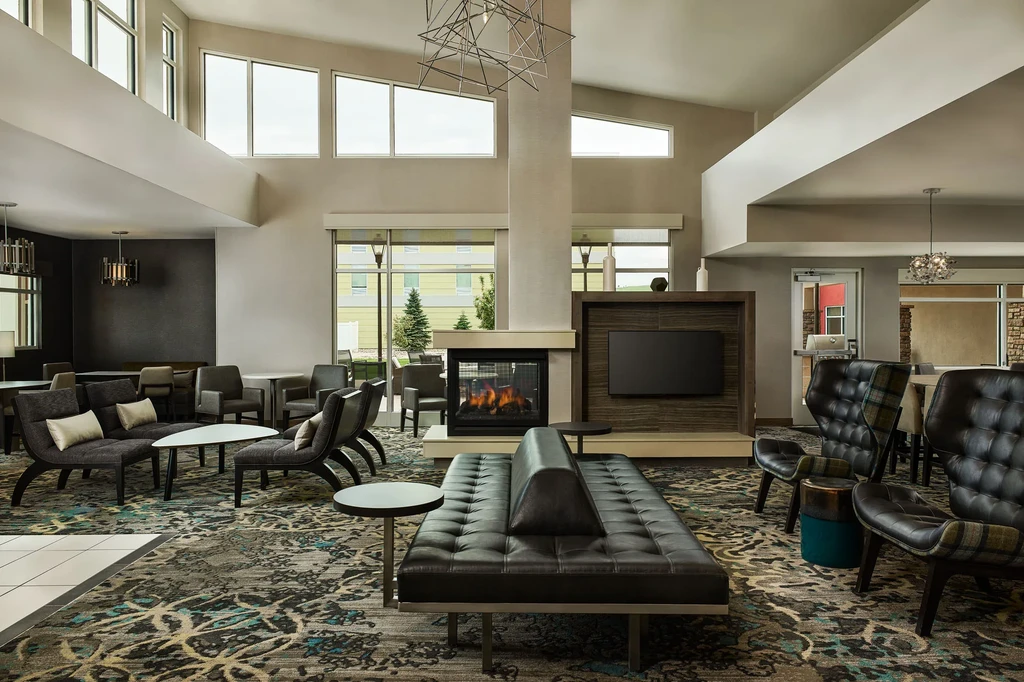 Modern, unoccupied lounge with a roaring fireplace, TV, and varied seating.