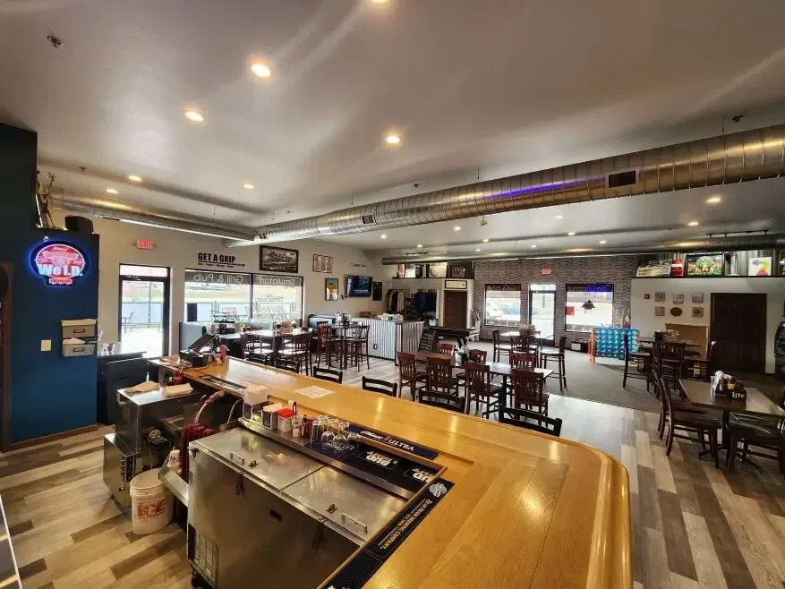 Empty casual restaurant bar with modern decor and a "WOLF" neon sign.