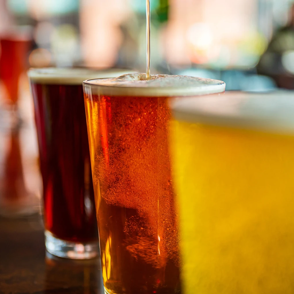 Close-up of amber beer being poured into a pint glass.