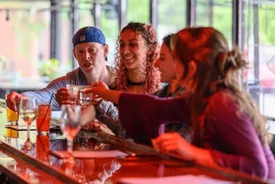 Four people clinking drinks at a bar counter.