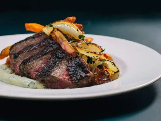 Sliced medium-rare steak, creamy sauce, caramelized onions, sweet potato fries.