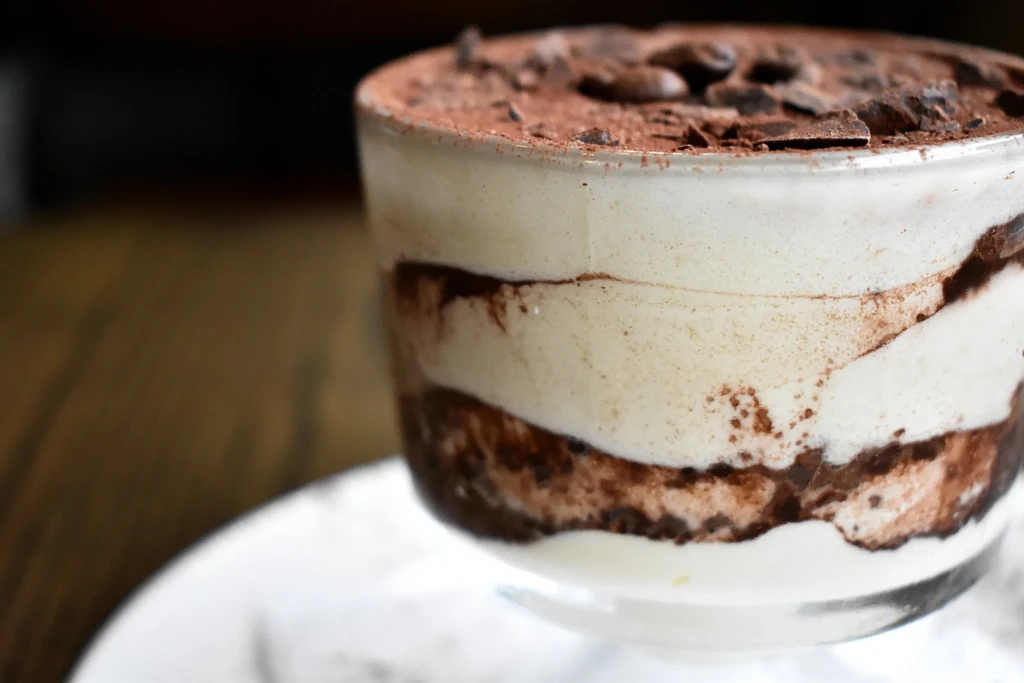Creamy layered dessert in glass, cocoa-dusted with chocolate shavings.