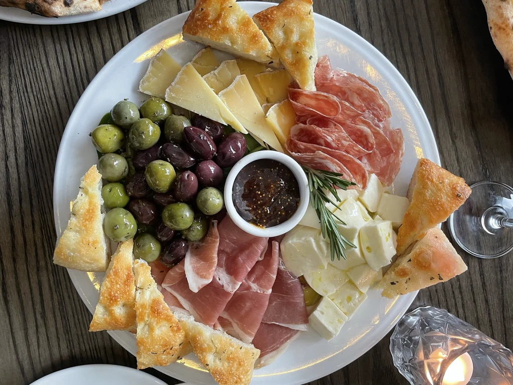 Overhead charcuterie board with cheeses, meats, olives, focaccia, and fig jam.