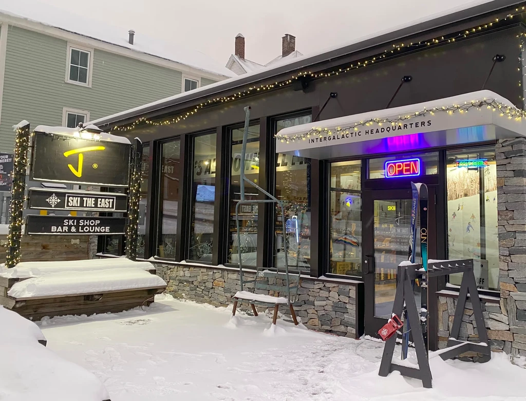 Snowy JT Ski Shop Bar & Lounge exterior with bright signs and lights.
