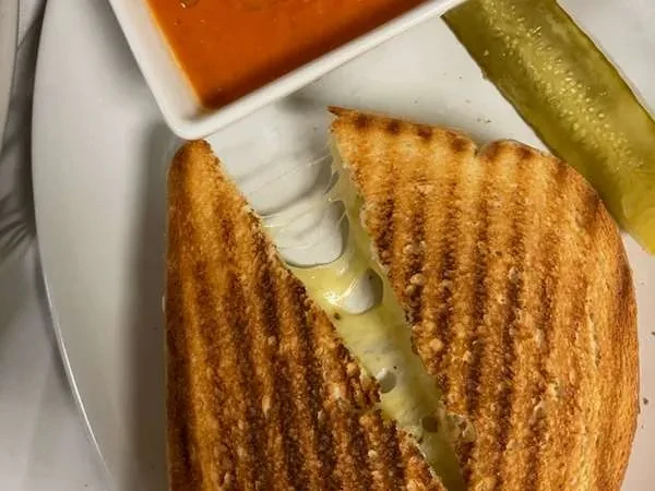 Grilled cheese with gooey stretching cheese, dipping sauce, and a pickle.
