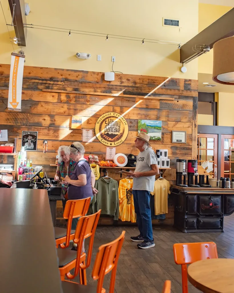 Interior of Vermont Creperie with counter, merchandise, and sunlit wood wall.