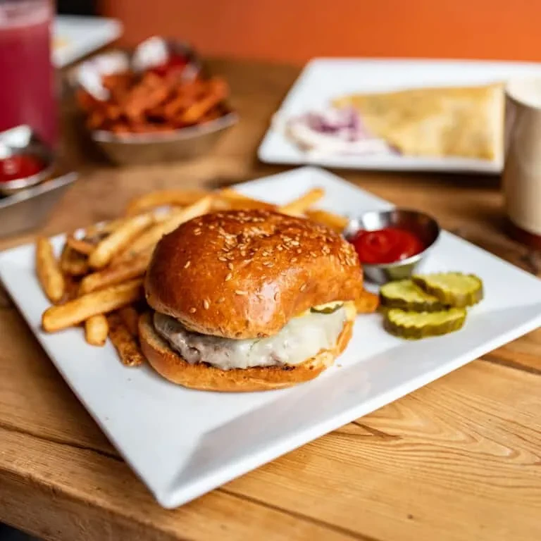 Cheeseburger with melted cheese, golden fries, ketchup, and pickles.