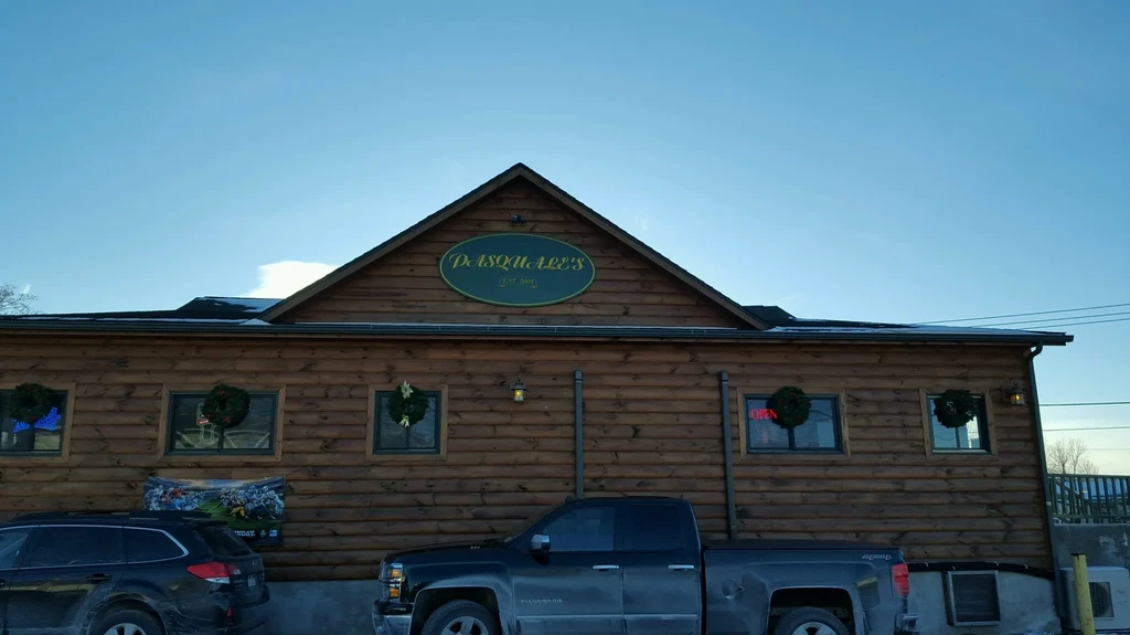Pasquale's log-cabin building exterior, decorated with snow, wreaths, and parked cars.