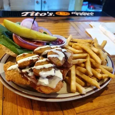Fried chicken sandwich with cheese, bacon, mushrooms, fries, and pickle.