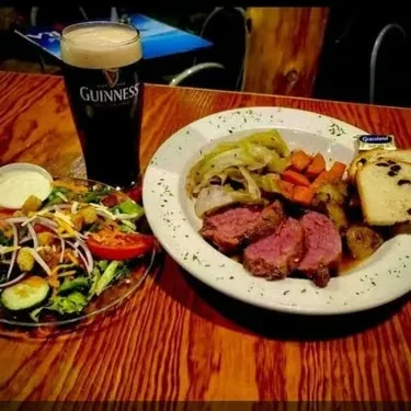 Roast beef dinner, garden salad, and Guinness stout on a pub table.
