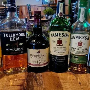 Four distinct Irish whiskey bottles on a wooden surface.