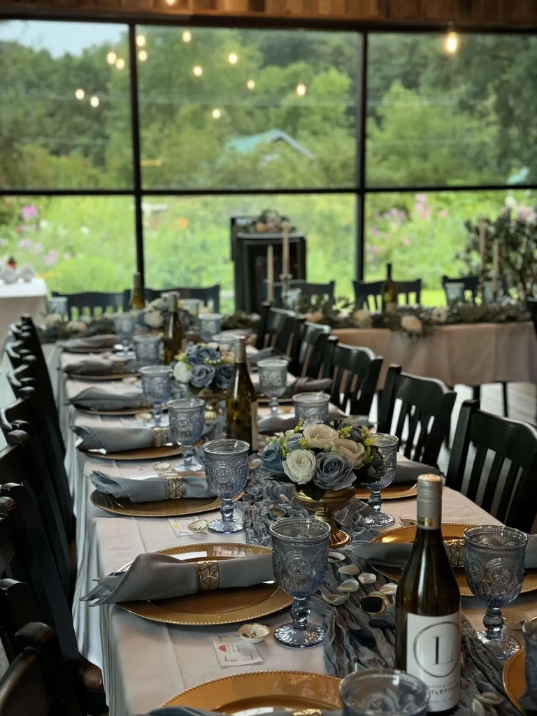 Elegantly set dining table with white and blue flowers, gold plates.