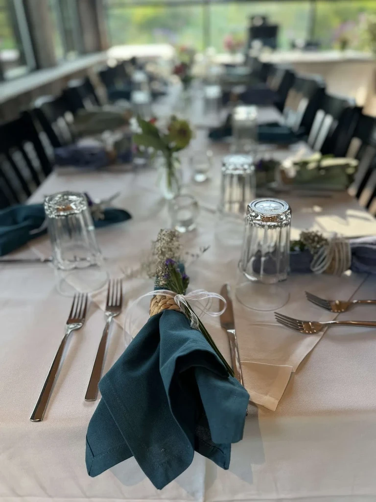 Elegant table set with white tablecloth, teal napkins, silverware, and glasses.