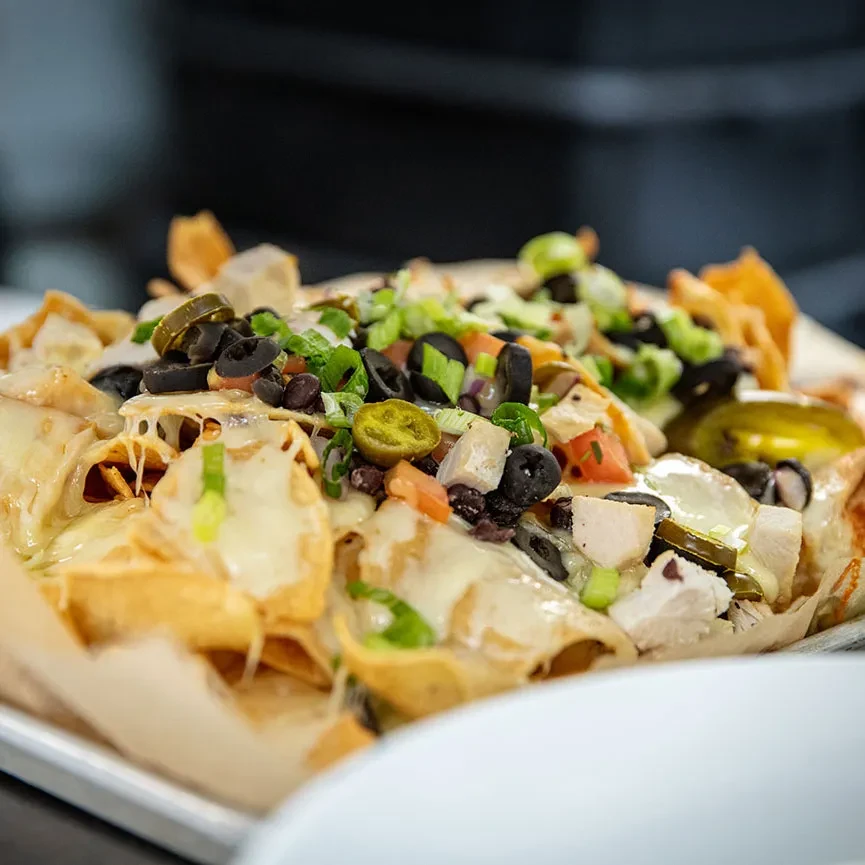 Nachos with melted cheese, chicken, olives, beans, tomatoes, jalapeños.