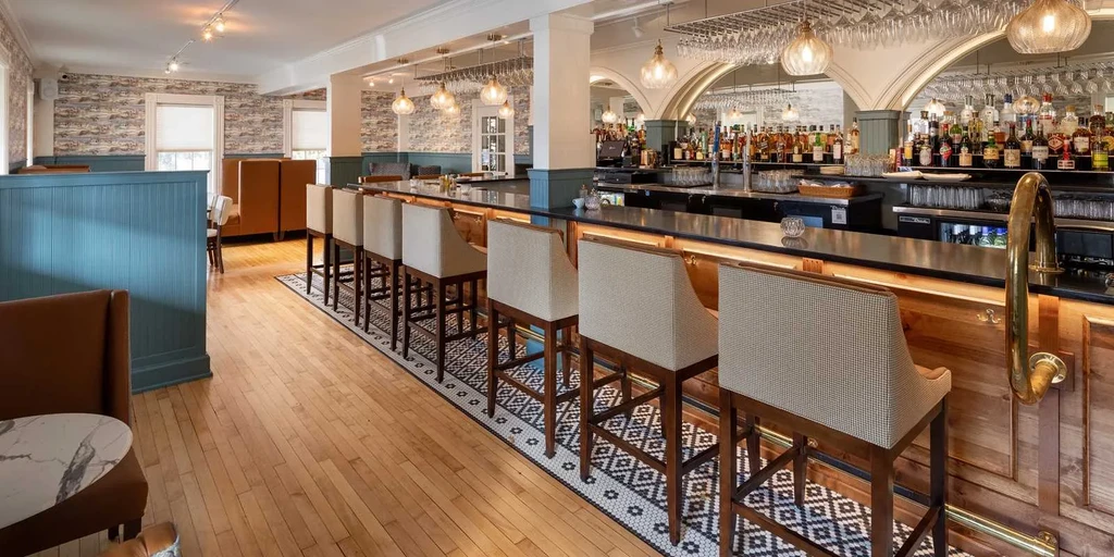 Upscale bar interior featuring warm lighting, mosaic floor, and arched mirrors.