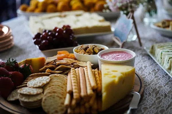 A well-arranged platter with cheese, crackers, strawberries, nuts, and dip.