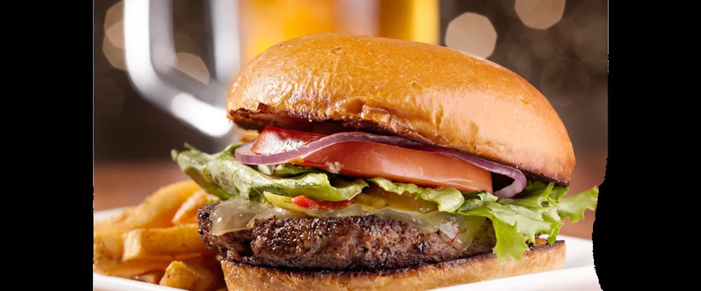 Steaming gourmet hamburger with golden fries on a white plate.