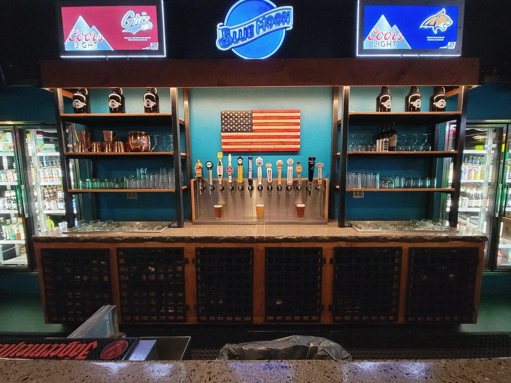 Unoccupied sports bar with beer taps, branded signs, and glassware.