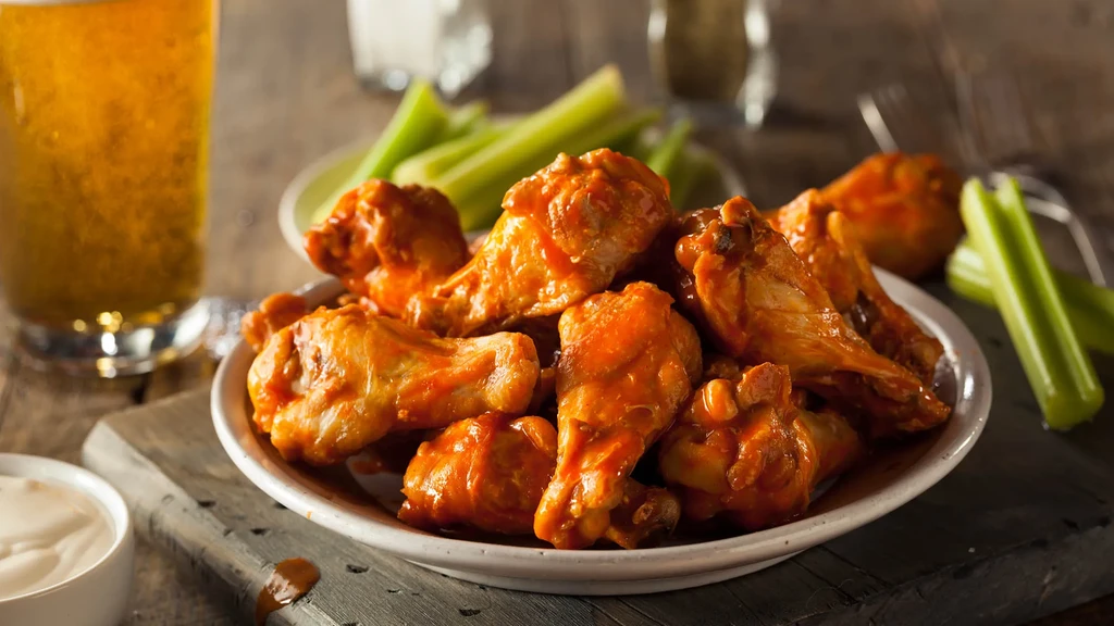 Close-up: Buffalo chicken wings, celery, dipping sauce, and beer.
