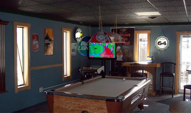 Interior of a bar with a pool table and TV showing sports.
