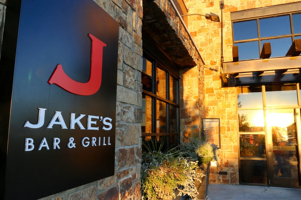 Jake's Bar & Grill sign on a stone building in golden sunlight.