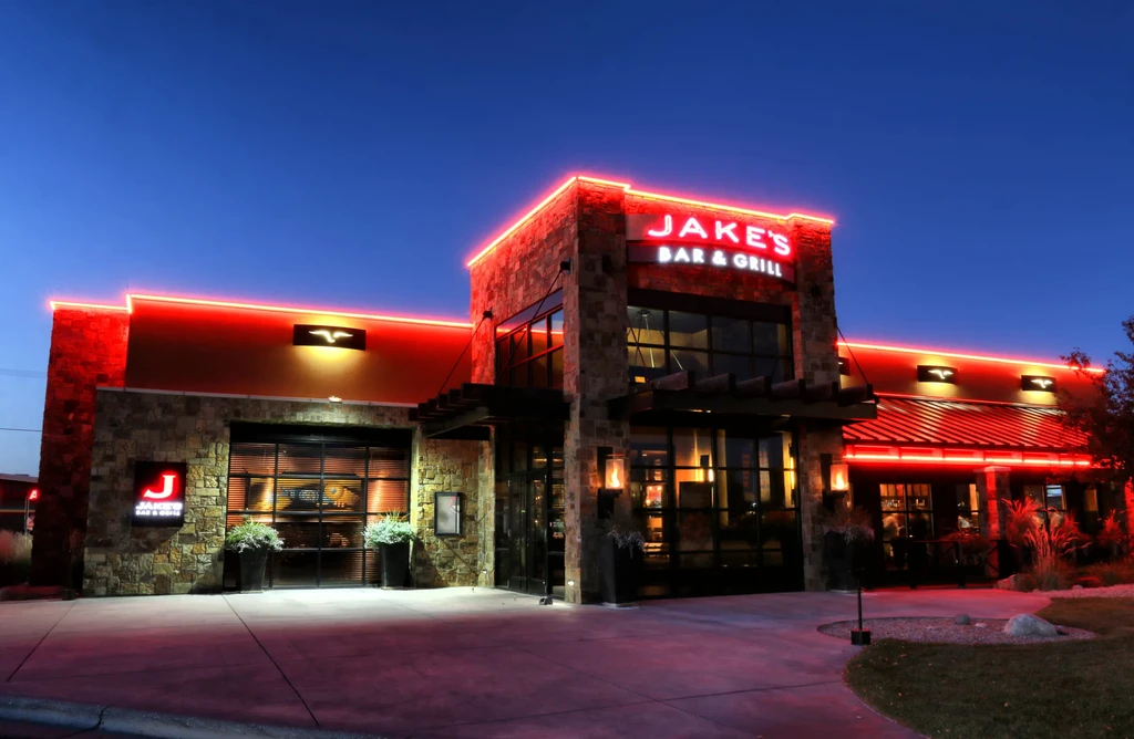 Exterior of Jake's Bar & Grill lit by red neon at night.