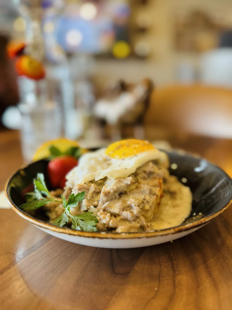Biscuits and sausage gravy, topped with a fried egg and parsley.