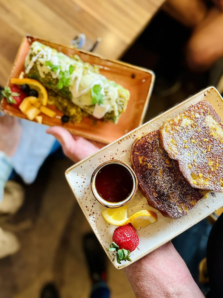 Two breakfast plates: French toast, green burrito, and fruit.