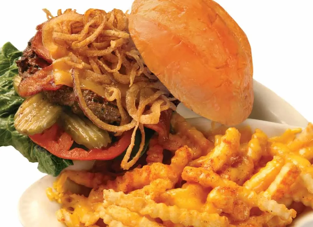 Gourmet burger with bacon, crispy onion strings, and cheese fries.