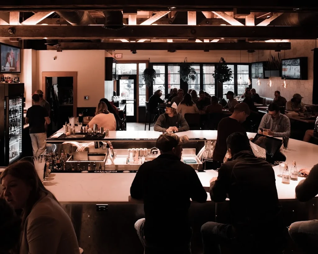 Lively restaurant interior with an L-shaped bar and industrial-chic decor.