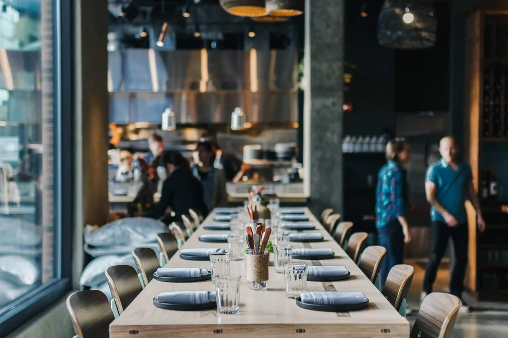 Long light wooden communal table set in modern restaurant.