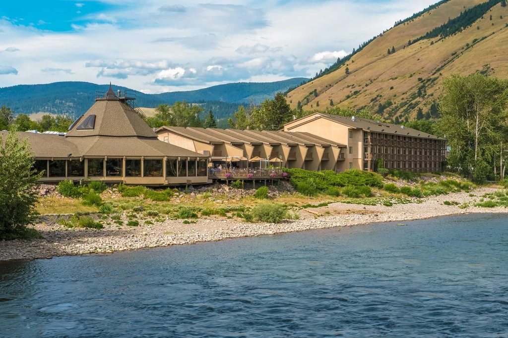 Riverside hotel with conical roof and outdoor dining deck.
