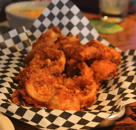 Crispy deep-fried appetizer in a metal basket on checkered paper.