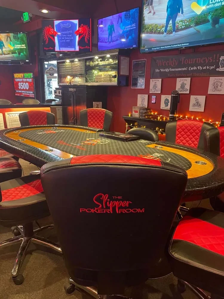 The Slipper Poker Room with table, red decor, multiple TVs.