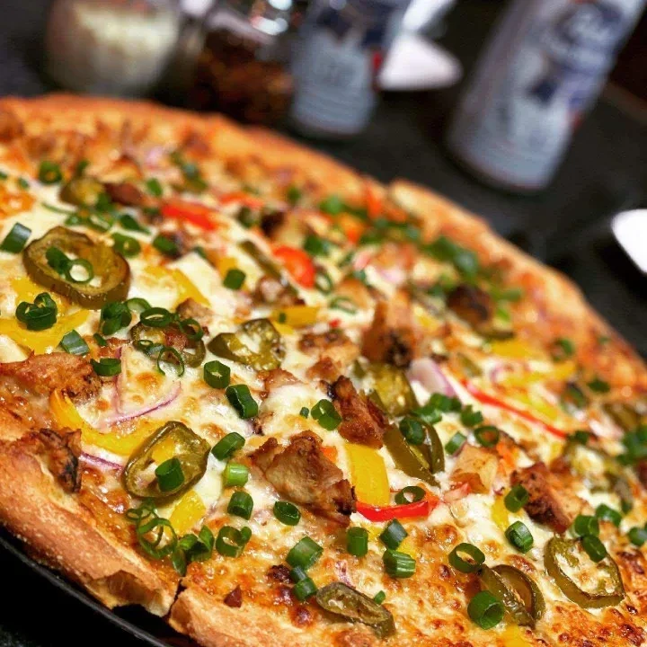 Vibrant pizza with chicken, cheese, bell peppers, onions, and jalapeños.