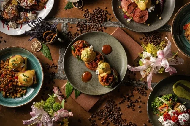 An overhead shot of several brunch dishes on a brown table with coffee beans.