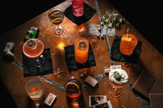 Overhead view of a copper table with various cocktails and bar items.