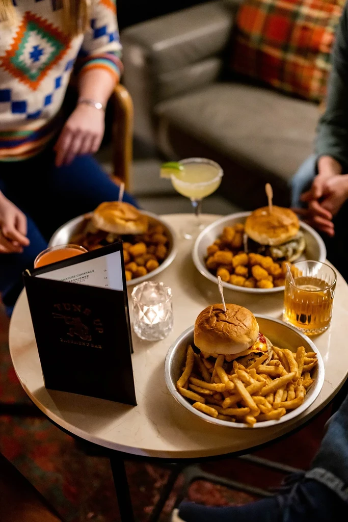 Overhead view of burgers, drinks, a lit candle, and a bar menu.