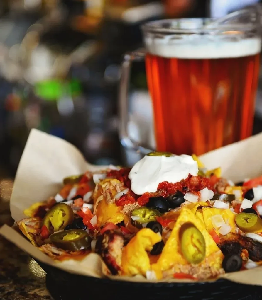 Nachos generously topped with cheese, shredded meat, jalapeños, and sour cream.