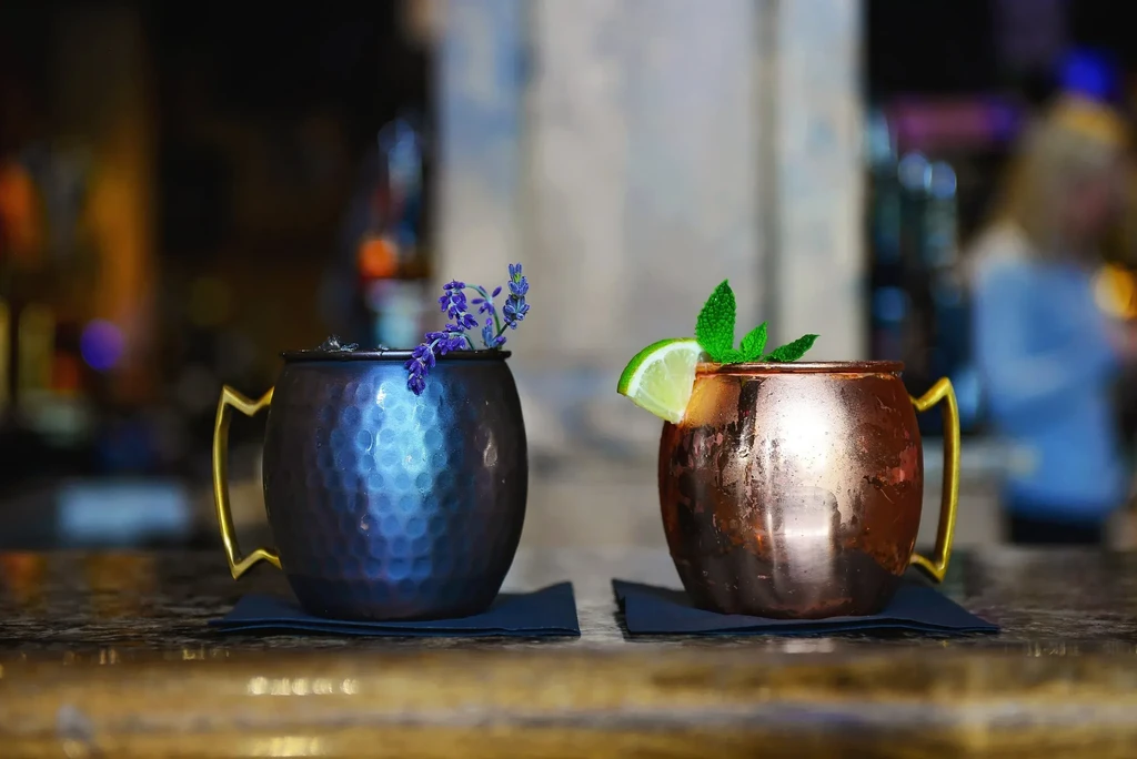 Two Moscow Mule cocktails, one dark blue, one traditional copper, garnished.