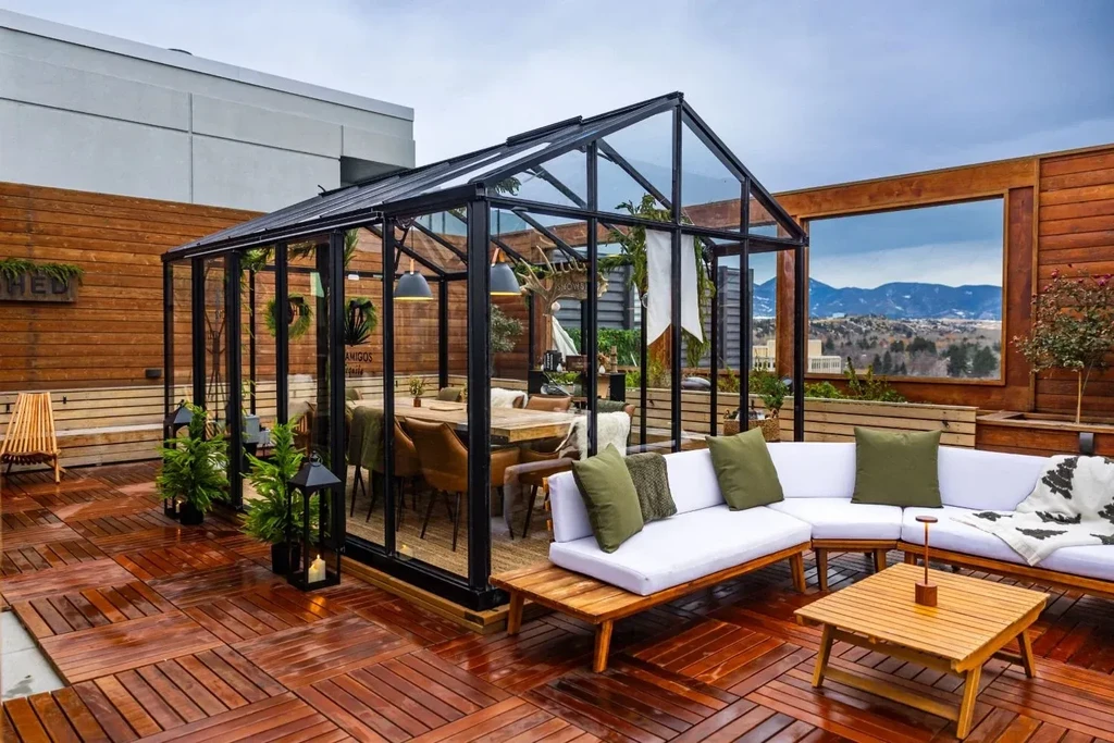 Stylish glass greenhouse dining and lounge area with mountain view.