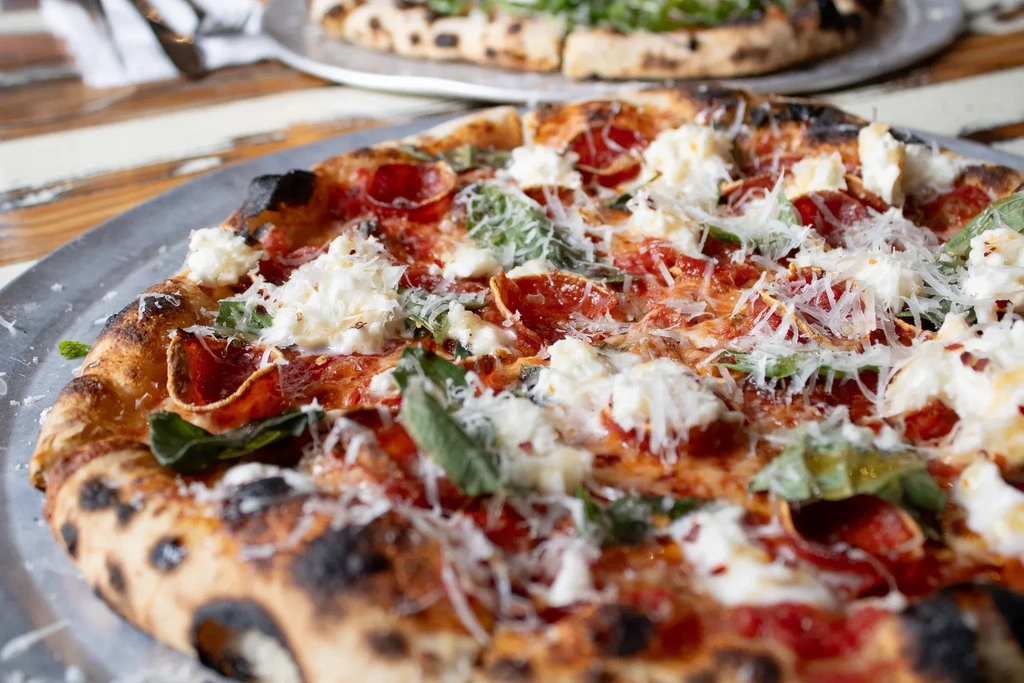 Fresh Neapolitan pizza with pepperoni, ricotta, basil, and grated cheese.
