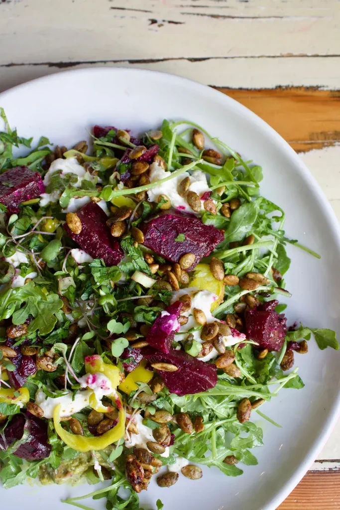 Salad with dark greens, red beets, creamy cheese, and pepitas.