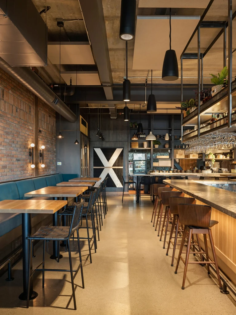 Empty industrial-chic restaurant interior with exposed brick and a bar.