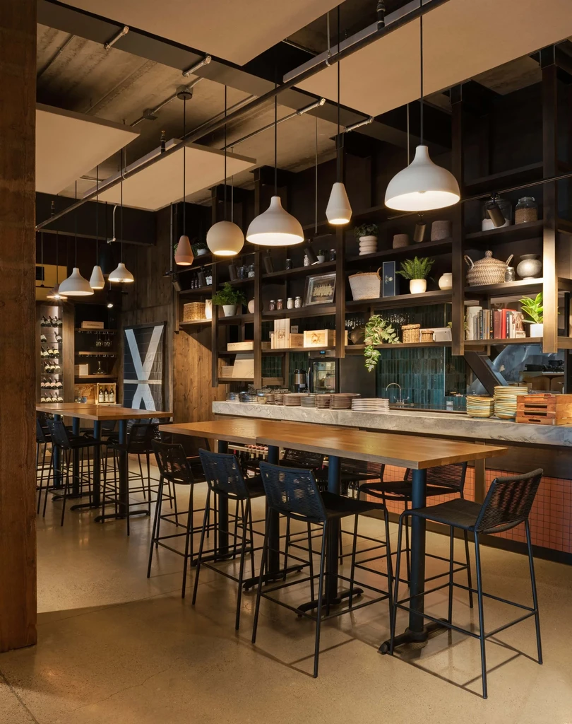 Modern restaurant interior with industrial-rustic decor, high-top tables, and styled shelves.