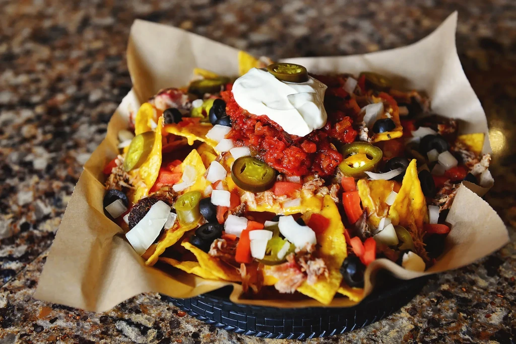 Piled high nachos topped with cheese, meat, salsa, and sour cream.