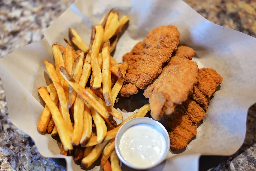 Basket with crispy golden fried chicken, thick-cut fries, and dipping sauce.
