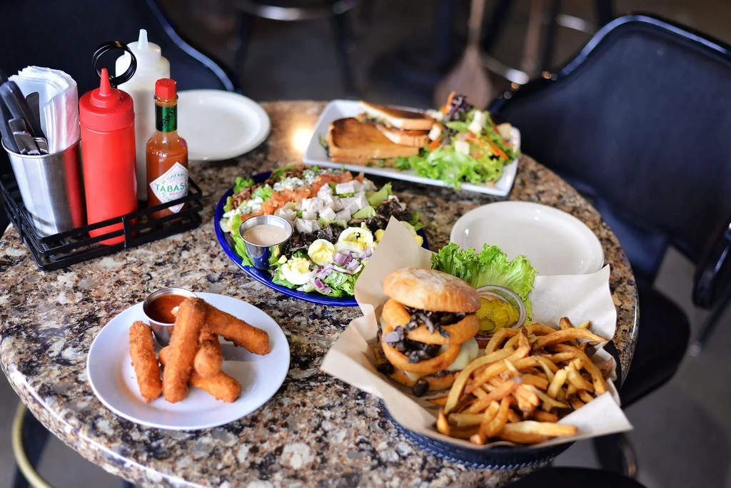Restaurant table laden with mozzarella sticks, salad, burger, and fries.