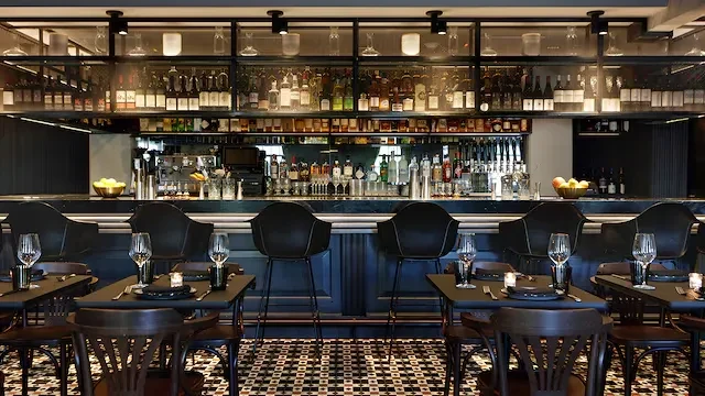 Upscale bar interior with a stocked counter, tables, and geometric floor.