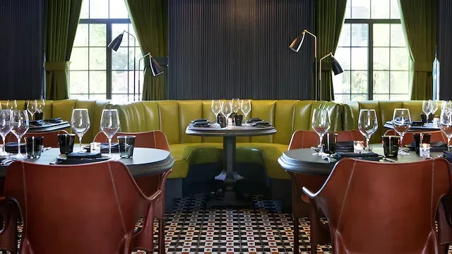 Modern restaurant dining room with a lime green banquette, geometric tile floor.
